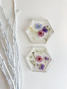 two glass plates with flowers painted on them next to branches and twigs in the background