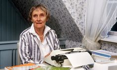 an older woman sitting at a desk with a typewriter and papers in front of her