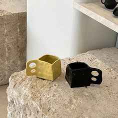 two black and gold vases sitting on top of a rock next to each other