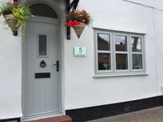 a white house with flowers hanging from it's windows and the number 5 on the front door