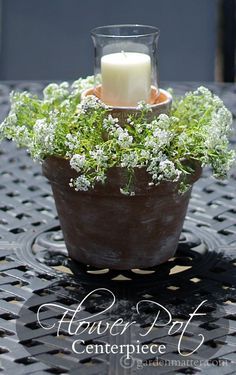 a candle sits in a potted plant on a table with the words flower pot centerpiece