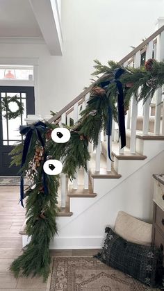 a christmas garland on the banister with eyes and pine cones hanging from it's side