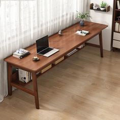 a wooden table with a laptop on top of it next to a book shelf and window