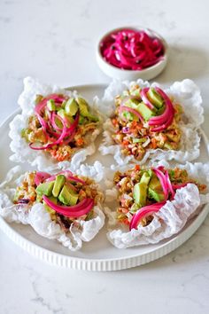 four appetizers are arranged on a plate with red cabbage and avocado