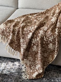 a brown and white blanket sitting on top of a couch next to a blue rug