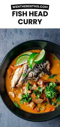 fish head curry in a black bowl with lime wedges