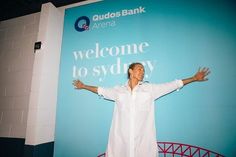 a man standing in front of a sign with his arms spread out to the side