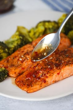 a plate with salmon, broccoli and cauliflower is being spooned