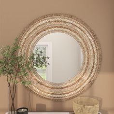 a round mirror hanging on the wall above a dresser with a plant and potted plant