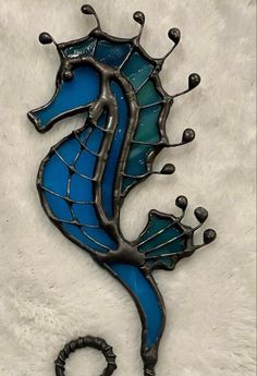 a seahorse made out of stained glass sitting on top of a white surface with black accents