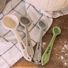 three measuring spoons sitting on top of a table next to a bowl and towel