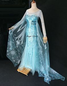 a blue dress with white snowflakes on it and a long cape over the shoulders