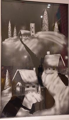 a black and white photo of a snowy town with trees in the window sill