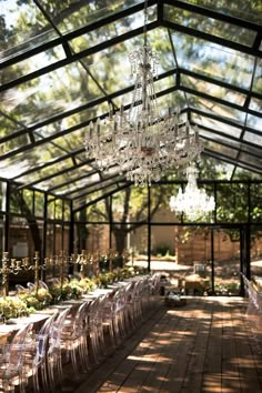 the inside of a glass house with tables and chairs set up for a formal function