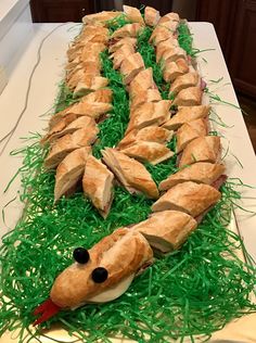 there is a very long cake made to look like a snake in the grass with bread on it