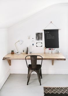 a desk with a chalkboard on the wall above it