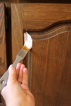 someone using a brush to paint a piece of wood with white paint on the top