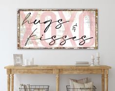 a sign that says hugs kisses on the wall above a wooden table with baskets underneath it