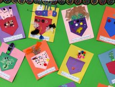 several different colored paper cards with pictures and magnets attached to them on a green surface