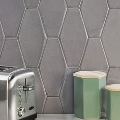 a silver toaster sitting on top of a counter next to a canister and cup