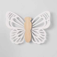 a wooden butterfly with white wings on a gray background, it is cut out from the wood