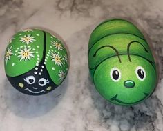 two painted eggs sitting on top of a marble counter covered in green and white designs