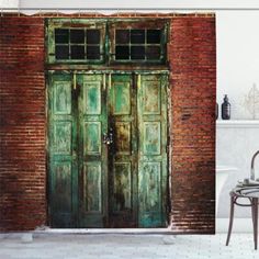 two green doors are open in front of a red brick wall and wooden flooring