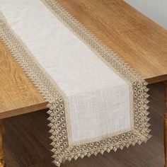 a wooden table topped with a white and beige table runner on top of a wooden table