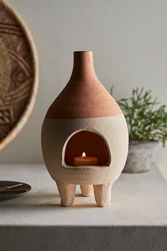 a small clay oven sitting on top of a table next to a potted plant