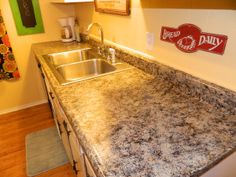 a kitchen with granite counter tops and stainless steel sink in the center, next to a red dairy sign on the wall