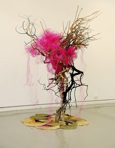 a sculpture made out of branches and pink flowers