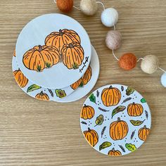 three paper plates with pumpkins on them sitting on a table next to some balls