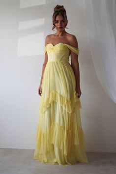 a woman in a yellow dress posing for the camera with her hands on her hips