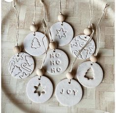 six ceramic christmas ornaments hanging from strings on a wooden floor with the words joy written in different languages