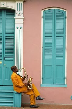 a man sitting on the side of a building with a saxophone in front of him