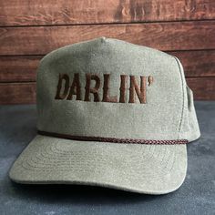 Vintage Style Darlin' Embroidered Faded Canvas Snapback Trucker Rope Hat with Free Shipping. White stitched text/logo. Condition is "New with tags". Shipped with USPS First Class. Step into the world of the great outdoors with our Darlin' Stitched Faded Canvas Rope Hat. With its faded canvas and rope accents, this hat exudes rustic charm and pays tribute to the iconic country music legends. Plus, enjoy free shipping on this vintage-inspired accessory that's perfect for any country music enthusia Vintage Curved Brim Hat With Letter Embroidery, Vintage Outdoor Baseball Cap With Embroidered Logo, Retro Adjustable Trucker Hat With Embroidered Logo, Vintage Curved Bill Hat With Embroidered Logo, Vintage Adjustable Hat With Letter Embroidery, Vintage Adjustable Snapback Hat With Embroidered Logo, Vintage Adjustable Baseball Cap With Embroidered Logo, Vintage Adjustable Hats With Embroidered Logo, Embroidered Trucker Hats