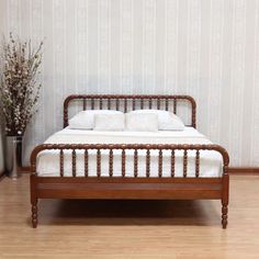 a wooden bed frame with white pillows on it