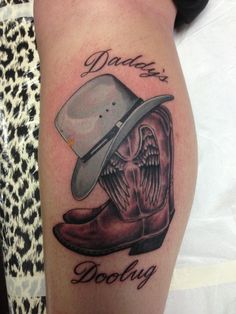 a tattoo with a cowboy hat and boots on it's thigh, which reads daddy doody