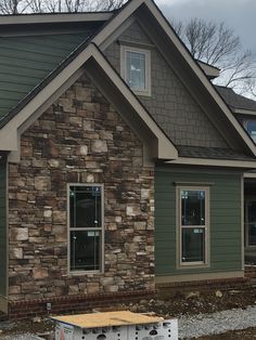 a house that is being built with some siding on the side and windows in front