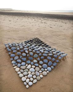 rocks arranged in the shape of an arrow on a sandy beach by the water's edge