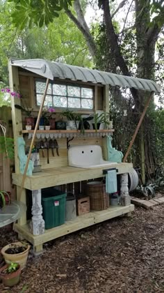 an outdoor kitchen made out of pallets in the woods with lots of potted plants