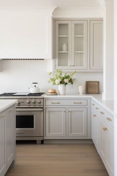 a kitchen with gray cabinets and white counter tops is pictured in this image, there are flowers on the stove