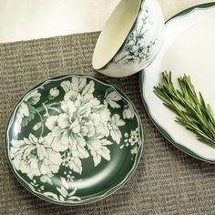 two plates with flowers on them are sitting next to each other and one has a sprig of rosemary in it