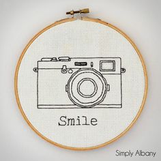 a cross stitch photo camera with the words smile on it