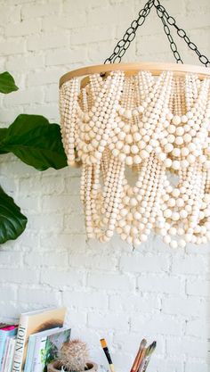 a chandelier made out of beads hangs from the ceiling in front of a white brick wall