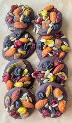 chocolate covered donuts topped with nuts and dried fruit on top of a countertop