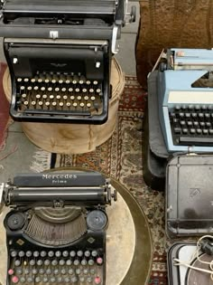 two old fashioned typewriters sitting on top of a table next to each other