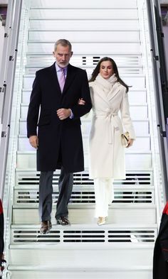 a man and woman walking down a flight of stairs in front of a white staircase