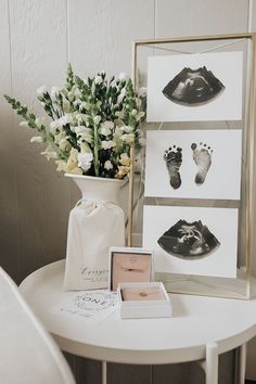 there is a vase with flowers and pictures on it next to a table that has baby's feet