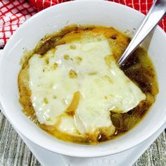 a white bowl filled with soup on top of a red and white checkered cloth